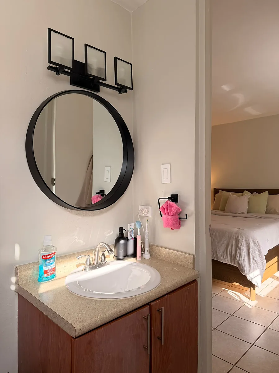 Baño de un Airbnb con espejo redondo, tocador despejado y toalla acomodada